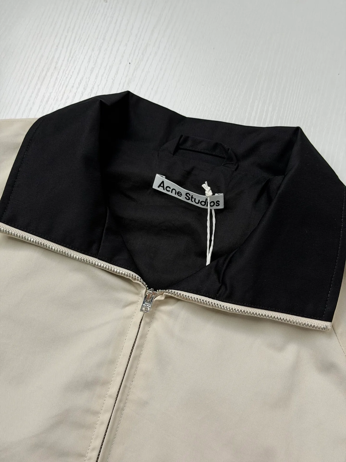 Acne Studio Retro Harrington jacket with embroidered letter logo on the back is made of custom-dyed poplin fabric with a Cream White body and Black lapels. The thickness, stiffness and matte texture of the fabric are completely in line with the original. The cutting process of the raglan sleeves, the smoothness of the zippers, the opening points of the pockets, and the routing of the pockets are all restored; the elastic elastic bands on the hem and cuffs are reproduced from the original ones, and the elasticity is in place, making it less likely to loosen and deform after long-term wear. Size：S/M/L/XL
